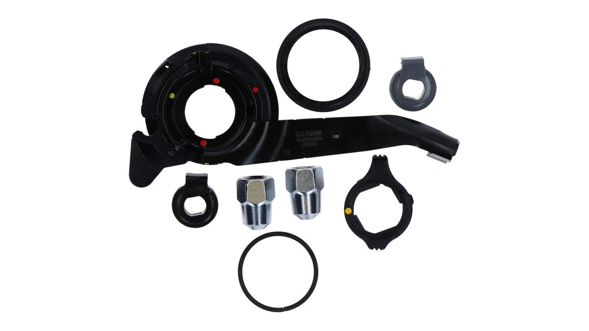 Ein Satz schwarzer und metallischer SHIMANO-Autoteile, einschließlich kreisförmiger Ringe, verchromter Sechskantmuttern und schwarzer Kunststoffteile aus dem Shimano SM-S700 8R/8L Kleinteile-Set, dargestellt auf weißem Hintergrund.