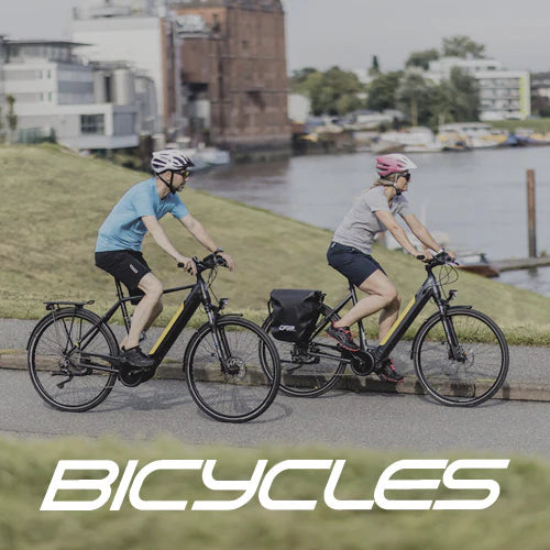 Zwei Fahrradfahrer auf Trekking E-Bikes von der Marke Bicycles in der Nähe eines Hafens.