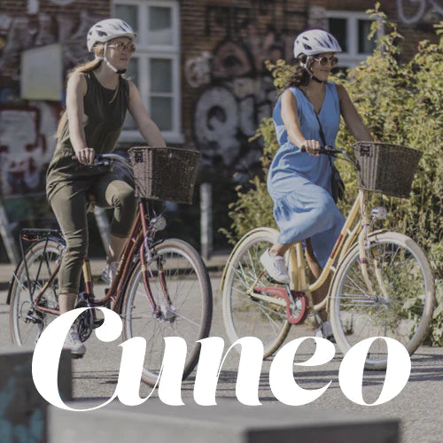 Zwei Fahrradfahrerinnen auf Cityrädern von der Marke Cuneo auf einer Straße.