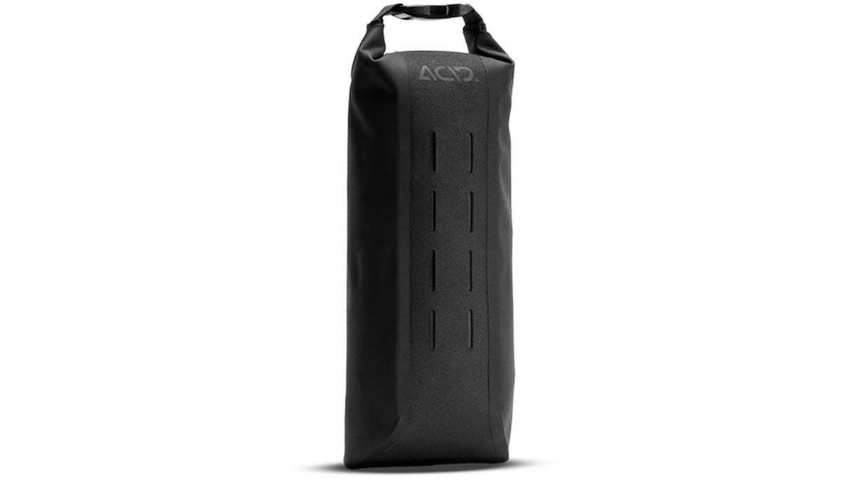 Die ACID PACK PRO 1 Gabeltasche von ACID ist eine hohe, rechteckige schwarze Trockentasche mit Rolltop-Verschluss und Aussparungen an der Vorderseite, die wasserdicht ist. Sie steht aufrecht auf weißem Grund - ideal für die Verwendung mit Ihrem Frontgepäckträger FORK CAGE.