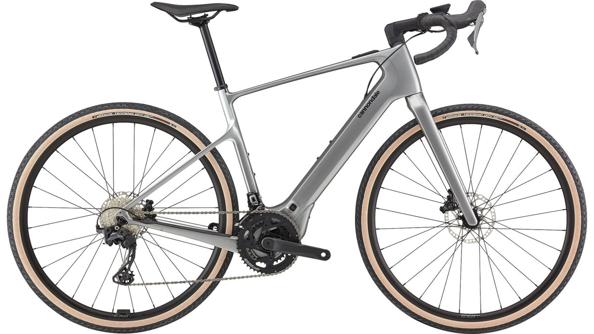 Ein schlankes silbernes CANNONDALE Synapse Neo AllRoad 2 E-Gravel-Bike mit tiefem Lenker, braunen Reifen, Scheibenbremsen und leichtem Rahmen wird von der Seite vor einem weißen Hintergrund gezeigt.