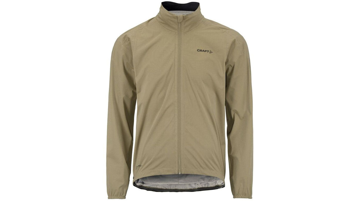 Die CRAFT ADV Hydro Jacket 2 M ist eine hellbraune, langärmelige Herren-Radjacke mit Frontreißverschluss, Stehkragen, winddichtem Material, verlängertem Rückensaum zur Abdeckung und dem CRAFT-Logo auf der linken Brustseite.