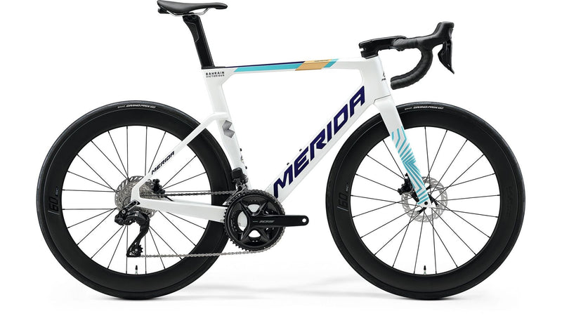 Ein weißes MERIDA Reacto 6000 Rennrad mit Carbonrahmen, schwarzen Laufrädern, tiefen Felgen, Scheibenbremsen und blau-gelben Akzenten wird im Seitenprofil vor weißem Hintergrund gezeigt.