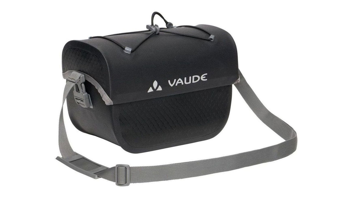 Die VAUDE Aqua Box 4 Lenkertasche ist eine schwarze, wasserdichte Lenkertasche mit grauem, verstellbarem Gurt, Überschlagverschluss und elastischen Kordeln an der Oberseite - ideal fürs Bikepacking. Das weiße VAUDE Logo ziert die Vorderseite und hält die Ausrüstung sicher und trocken.